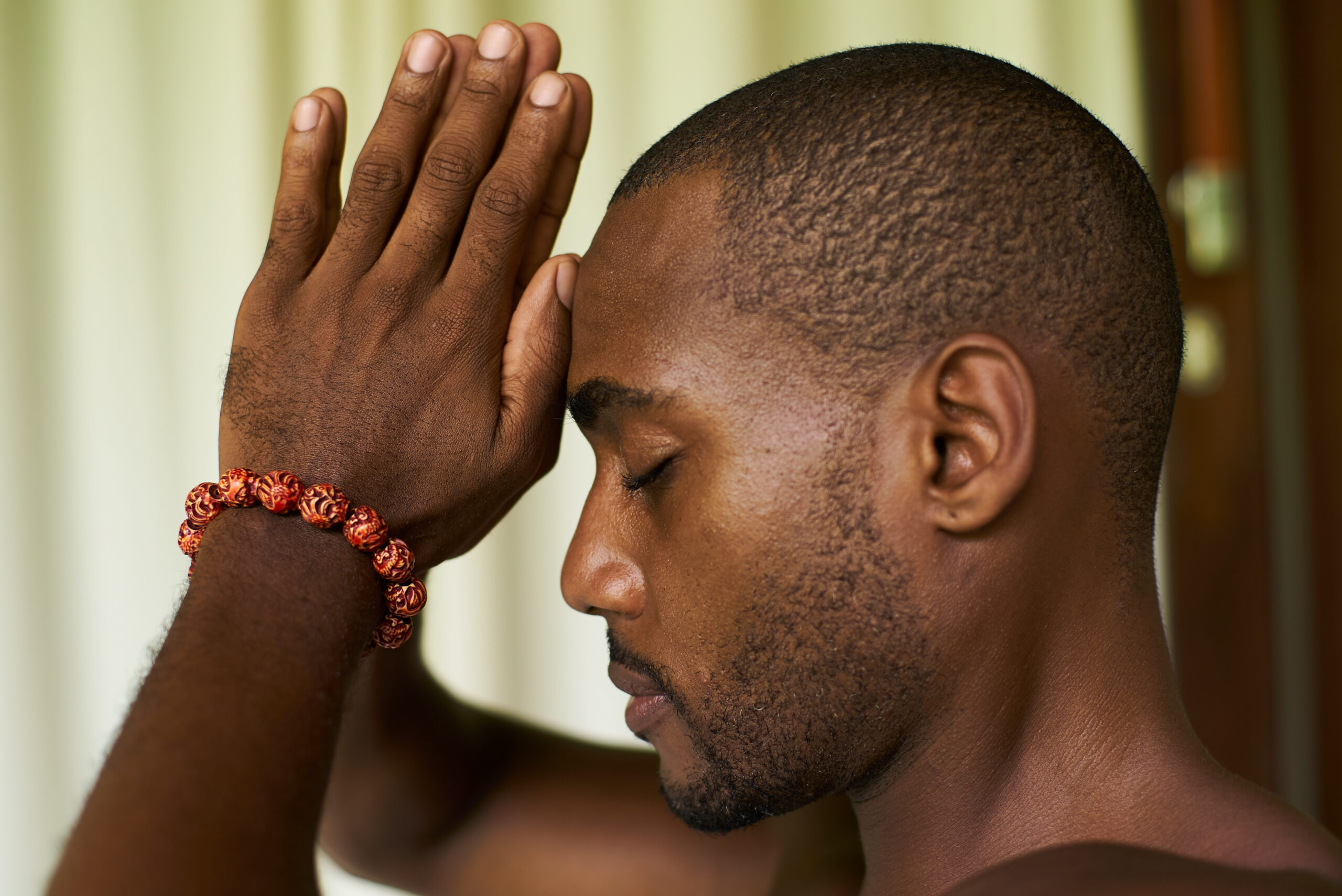 portrait of a handsome african american male put praying hands to his forehead